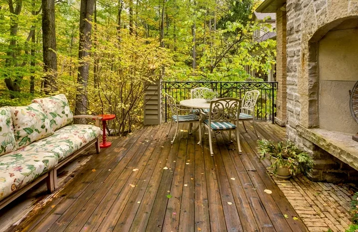 Freshly stained deck boards beside a stone fireplace wall