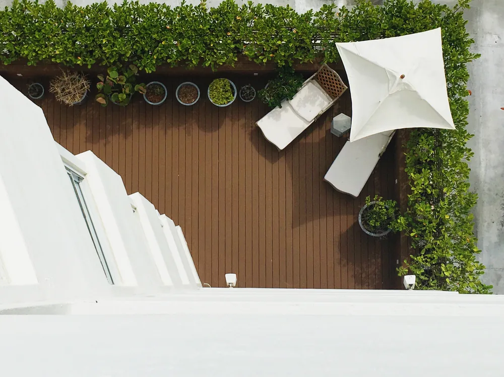 Rooftop terrace with brown deck boards, planters and a white umbrella