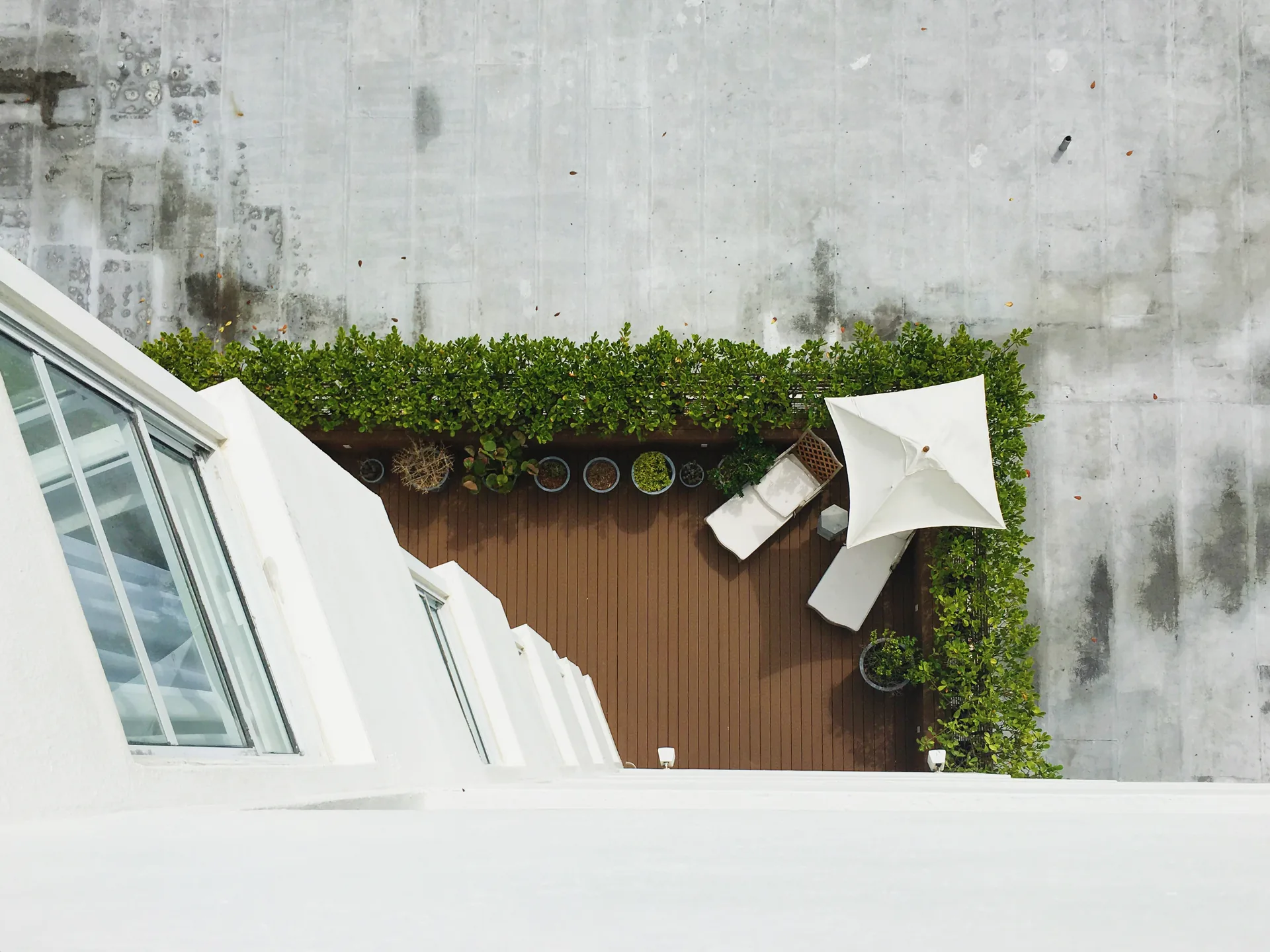 Rooftop terrace with brown deck boards, planters and umbrella from above